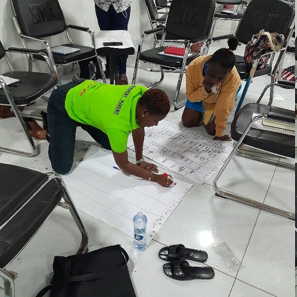 Participants working on a large flipchart on the floor during a practical exercise